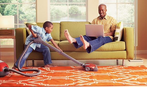 boy vacuming carpet while parents relax