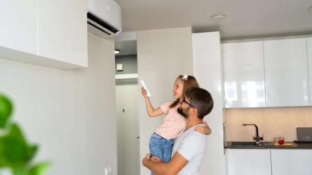 girl is turning on air condinioner with remote