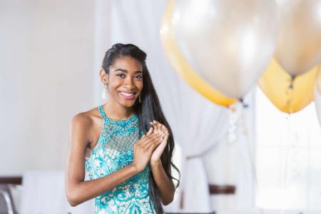 Smiling teenage girl in a formal dress getting ready for a school dance
