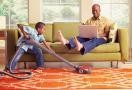 boy vacuming carpet while parents relax