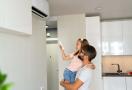 girl is turning on air condinioner with remote 