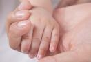 baby holding moms hand